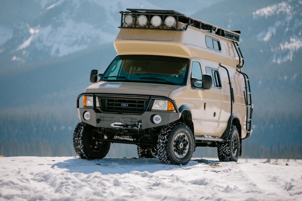 A beige Ford E-Series van in the snow.